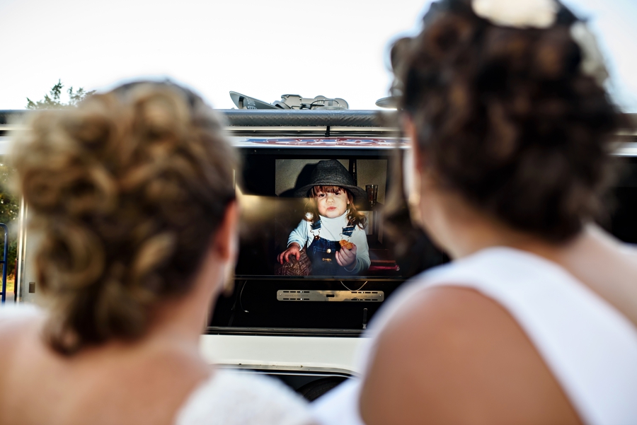 Two brides watching a slideshow at their LGBTQ wedding.
